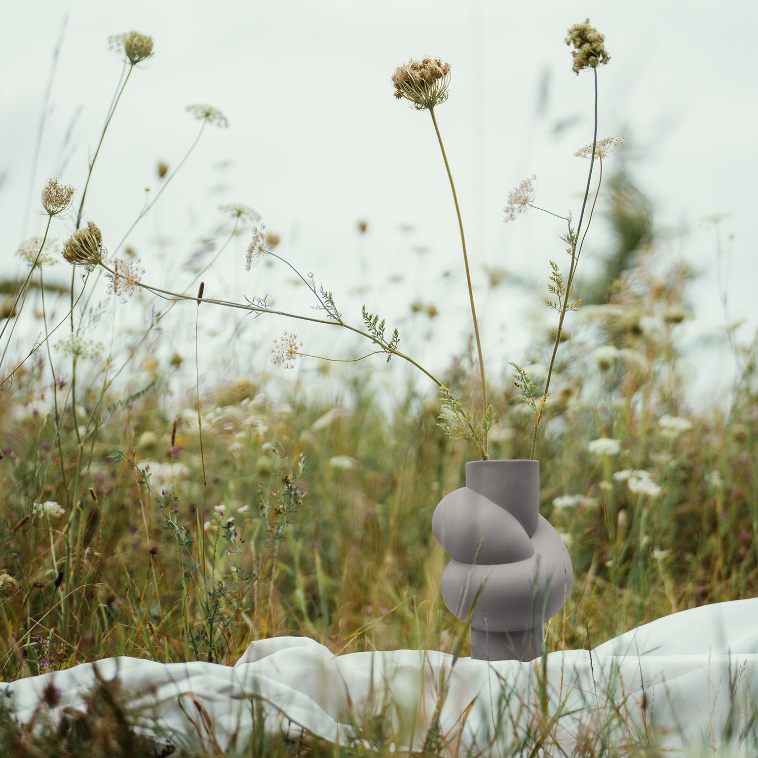 Node Lava with scattered meadow branches stands on a white blanket in the middle of a flower meadow.